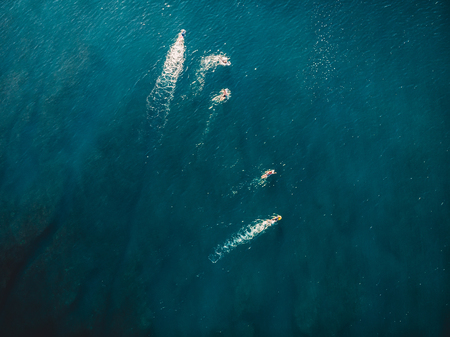 Surfers in blue ocean waiting wave. Aerial view with droneの写真素材