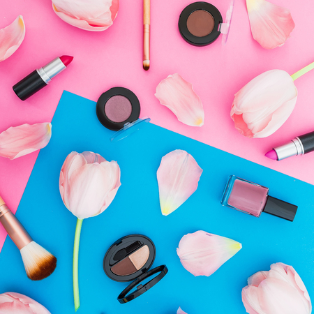 Beauty concept with tulips flowers and cosmetics on blue and pink background. Top view. Flat lay. Spring timeの写真素材