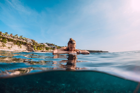 Surfer woman relax and floating at surfboard. Surf girl in ocean.