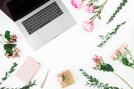 Frame with laptop, diary, pen, gift box and pink flowers and eucalyptus branches on white background. Flat lay. Top view. Feminine compositionの写真素材