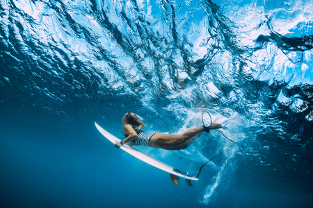 Surfer woman with surfboard dive underwater with ocean wave.の写真素材