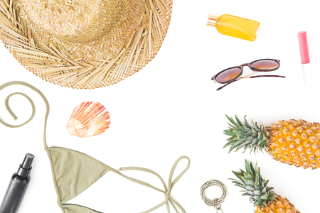 Frame of pineapple fruits, sun glasses, straw hat and bikini swimwear on white background. Flat lay, top view.の写真素材