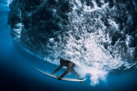 Attractive surfer woman dive underwater with under big wave.の写真素材