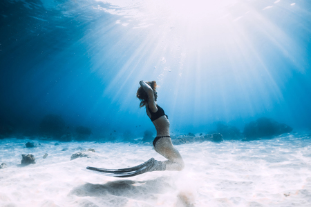 Woman freediver with pose over sandy sea with fins. Freediving underwater in Hawaiiの写真素材
