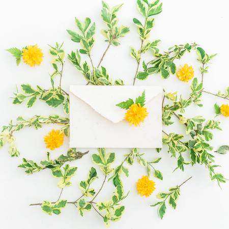 Yellow flowers and envelope on white background. Flat lay, Top view. Floral spring backgroundの写真素材