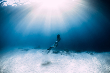 Woman freediver in bikini over sandy sea with fins. Freediving underwater in blue oceanの写真素材