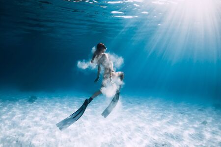Woman freediver with fins and white sand over sandy sea. Freediving underwater in blue oceanの写真素材