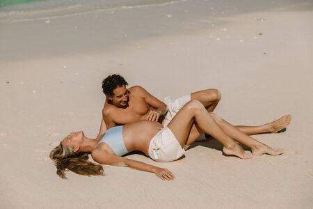 Pregnant woman with husband expecting baby at tropical beachの写真素材