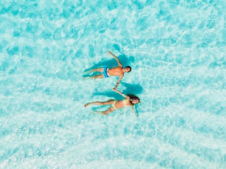 Pregnant woman with husband swim in blue sea. Aerial viewの写真素材