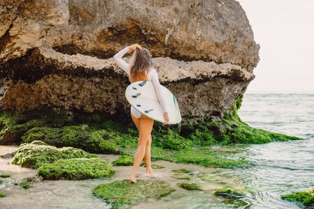Surfer girl with surfboard. Surfing in ocean