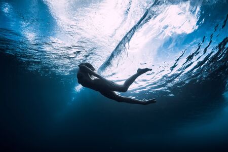 Young woman dive underwater with under barrel waveの写真素材
