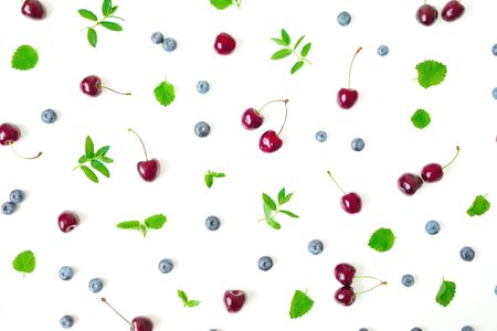 Cherry and blueberries with mint leaves on white background. Summer food frame. Top view. Flat layの写真素材