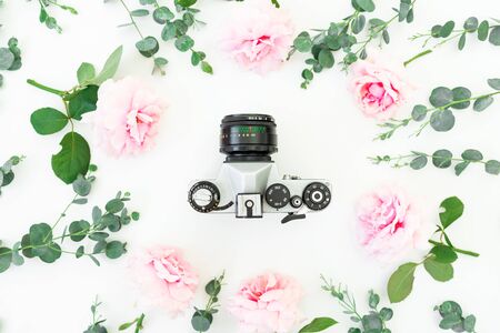 Flower composition of roses with eucalyptus branches and old retro camera on white background. Flat lay, top viewの写真素材