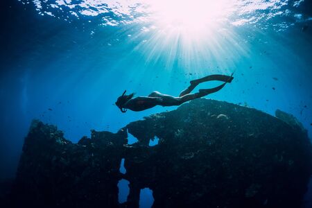 Woman freediver glides with fins at wreck ship. Freediving in blue ocean near wreckの写真素材