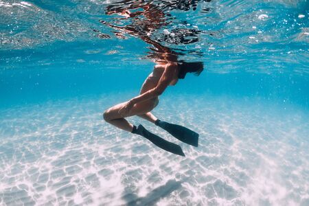 Woman free diver with fins posing over sandy sea. Freediving underwater in blue oceanの写真素材