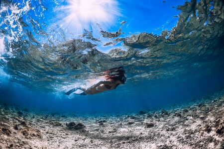 Free diver woman with fins glides over corals in blue ocean.の写真素材