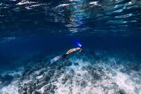 Woman freediver with fins glides underwater in seaの写真素材