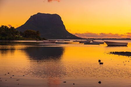 Fishing boats in ocean at sunset time. Le Morn mountain on background in Mauritius.の写真素材