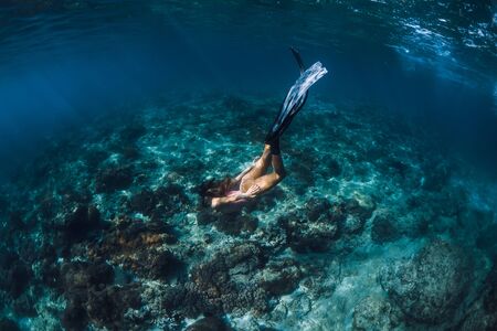 Woman freediver with fins underwater. Freediving in blue ocean