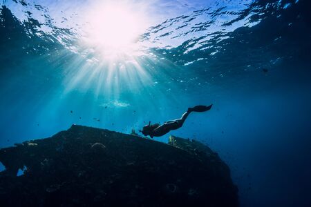 Free diver girl in pink swimwear with fins swimming underwater at wreck ship. Freediving in the oceanの写真素材