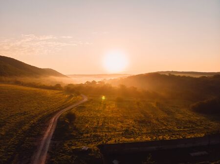 Aerial view of forest with warm sunset or sunrise and fog.