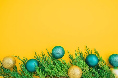 Christmas winter concept made of evergreen branches and balls decoration on yellow background. Flat lay, top view. Copy spaceの写真素材