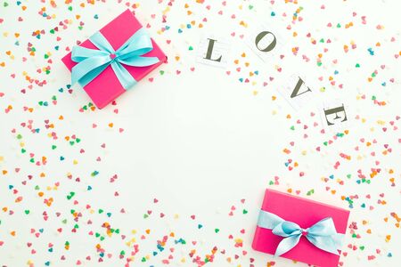 Valentines day composition with Love word, gifts and colorful confetti on white background. Copy space. Flat lay, top view.の写真素材