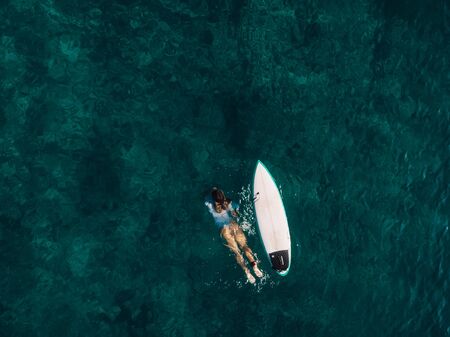 March 02, 2019. Bali, Indonesia. Aerial view of attractive surfer woman relax with surfboard in tropical ocean.のeditorial素材