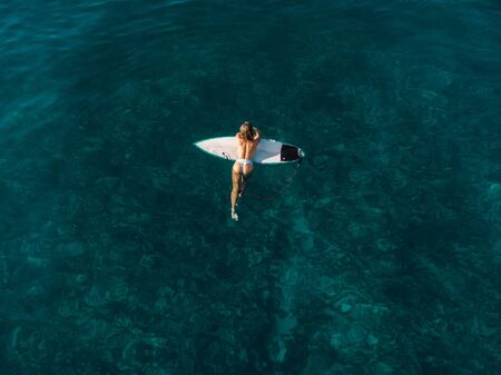 March 02, 2019. Bali, Indonesia. Aerial view of attractive surfer woman relax with surfboard in...