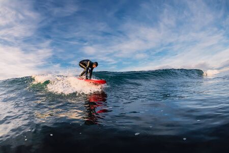 December 28, 2019. Anapa, Russia. Surfer in wetsuit on longboard and sea wave. Winter surfing in...
