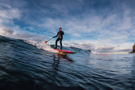 December 28, 2019. Anapa, Russia. Stand Up Paddle surfing on waves. SUP board and surfer in wetsuit...