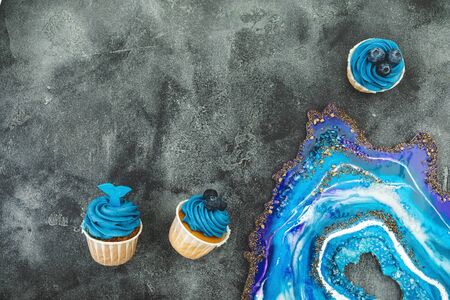 Blueberry muffins with blue cream and resin art on dark background. Flat lay, top viewの写真素材