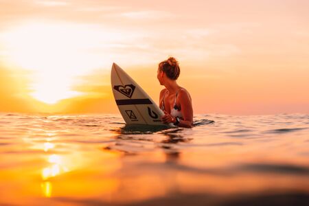 25 april 2019. Bali, Indonesia. Attractive surfer woman on a surfboard in ocean. Surfgirl at sunset