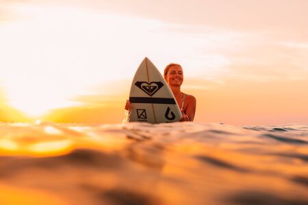 25 april 2019. Bali, Indonesia. Attractive surfer woman on a surfboard in ocean. Surfgirl at sunset