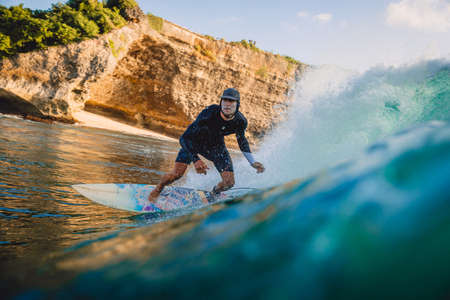 March 15, 2020. Bali, Indonesia. Surfer man on surfboard during surfing. Surfer ride on ocean wave.