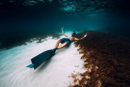 Freediver man with freediving fins relax over sandy bottom in blue oceanの写真素材