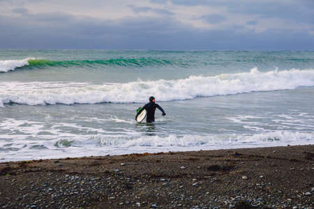 November 22, 2019. Crimea, Russia. Surfer in wetsuit with surfboard at beach.のeditorial素材