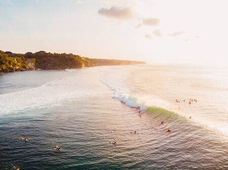 Aerial view of ocean with waves, surfers and warm light. Drone view in Baliの写真素材