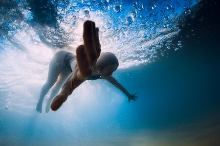 Woman dive without surfboard under ocean wave. Underwater duck dive under wave and sandy bottomの写真素材