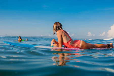 April 16, 2020. Bali, Indonesia. Surf girl relax on surfboard. Surfers in ocean during surfing.のeditorial素材