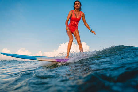 April 16, 2020. Bali, Indonesia. Surf girl ride on surfboard. Surfers in ocean during surfing.
