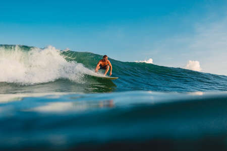 April 16, 2020. Bali, Indonesia. Surf girl ride on surfboard. Surfers in ocean during surfing.