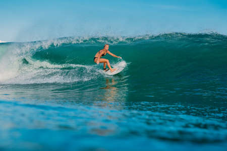 April 16, 2020. Bali, Indonesia. Surf girl ride on surfboard. Surfers in ocean during surfing.のeditorial素材