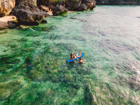 June 06, 2020. Bali, Indonesia. Aerial view of family with child and surfboard in ocean. Surfers family relax in waterのeditorial素材