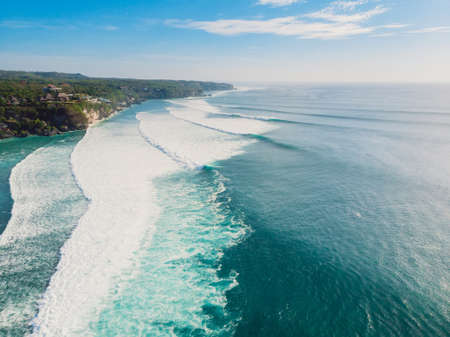 Surfing waves in ocean and coastline of Bali. Aerial view of surf spot.