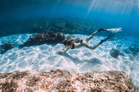 Woman freediver posing over sandy bottom with fins. Freediving in blue ocean at Hawaii islandsの写真素材