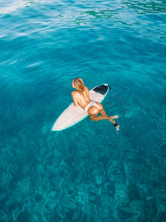 Attractive surfer woman on surfboard in blue ocean. Aerial viewの写真素材