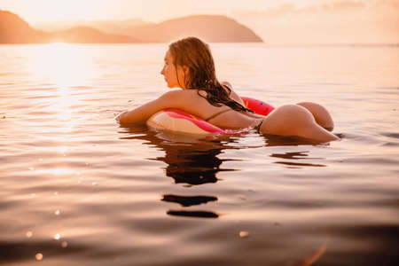 Young attractive girl with sexy body relax in the sea at warm sunsetの写真素材