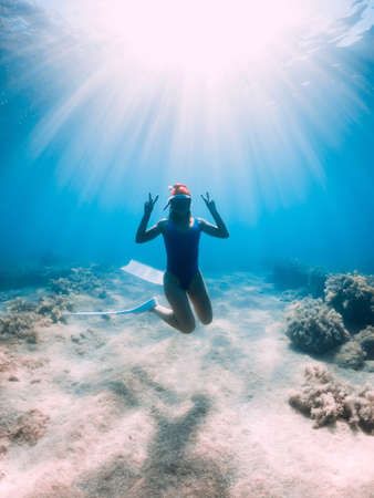 Happy freediver woman with New year cap glides underwater in blue ocean. Christmas holidays conceptの写真素材