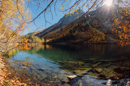Mountain lake with transparent water and colorful autumnal trees. Mountains and lakeの写真素材